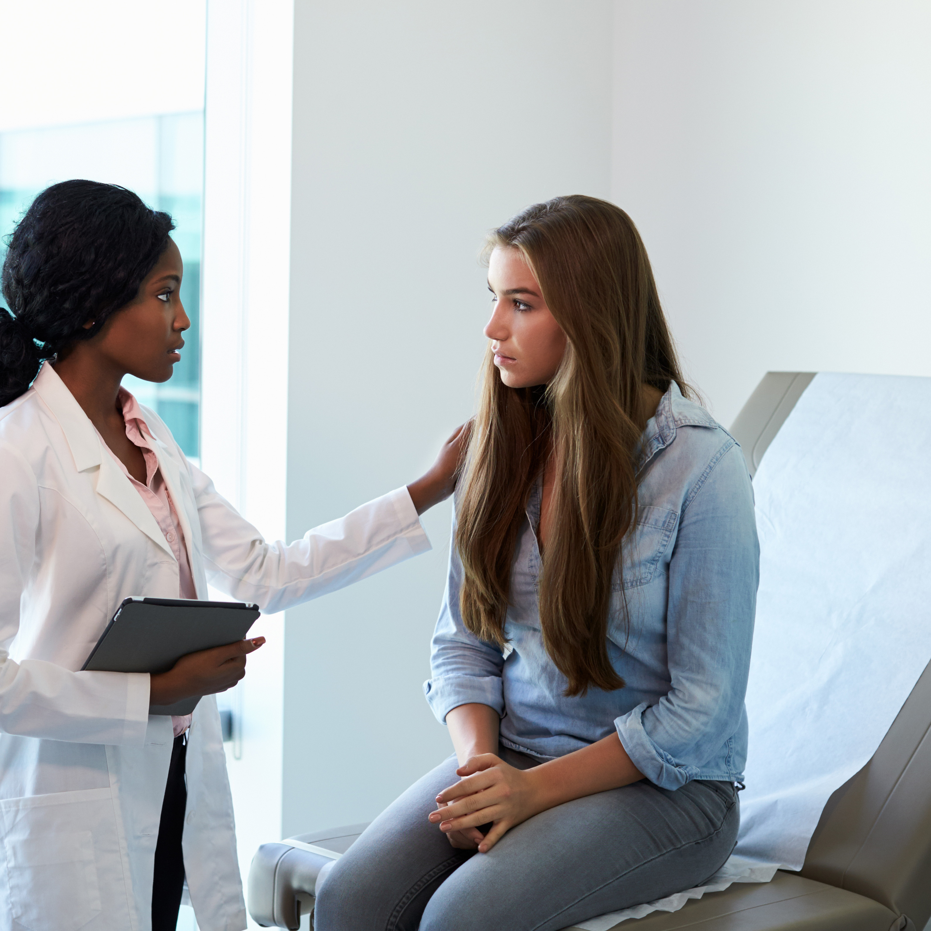 Doctor Talking To Unhappy Teenage Patient In Exam Room: Enter key opens full-screen view with caption; escape key exits full screen.