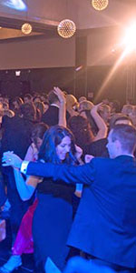 Well dressed people dancing in a blue lit room with singer on stage