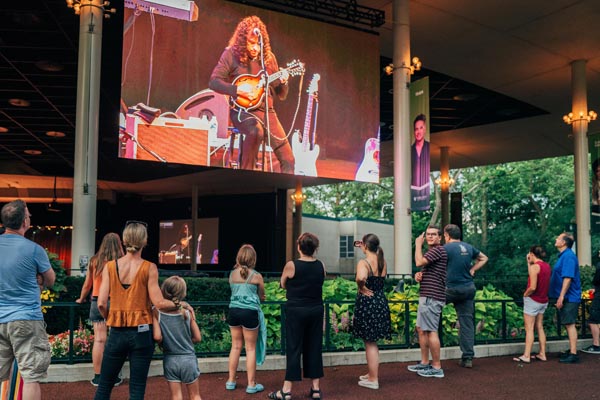 Guests watching a mandolinist's performance on a screen outside the Pavilion