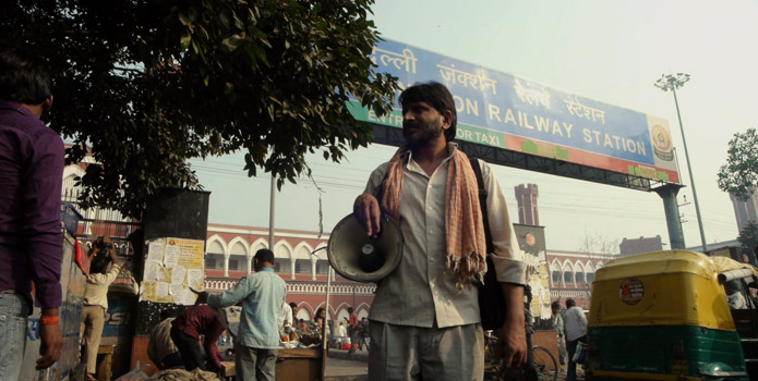 a man stands in front of a Railway station sign in Delhi