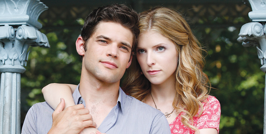 a man and a woman stand facing the camera. Her arm is draped over his shoulder.