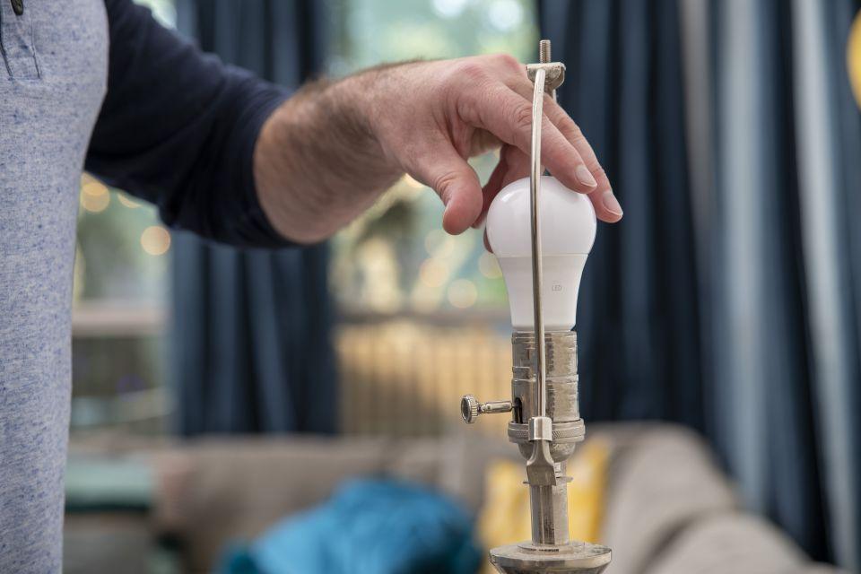 Photo image of a man changing out an LED bulb in a light fixture.