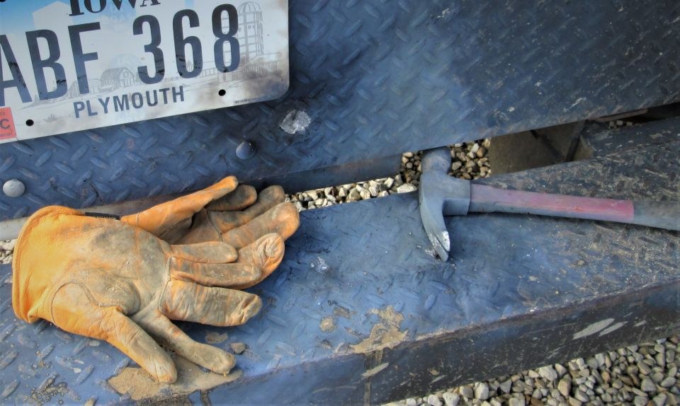 Image shows the back bumper of the truck where the injured crew member's gloves lay along withthe hammer that was fused with the truck bumper.