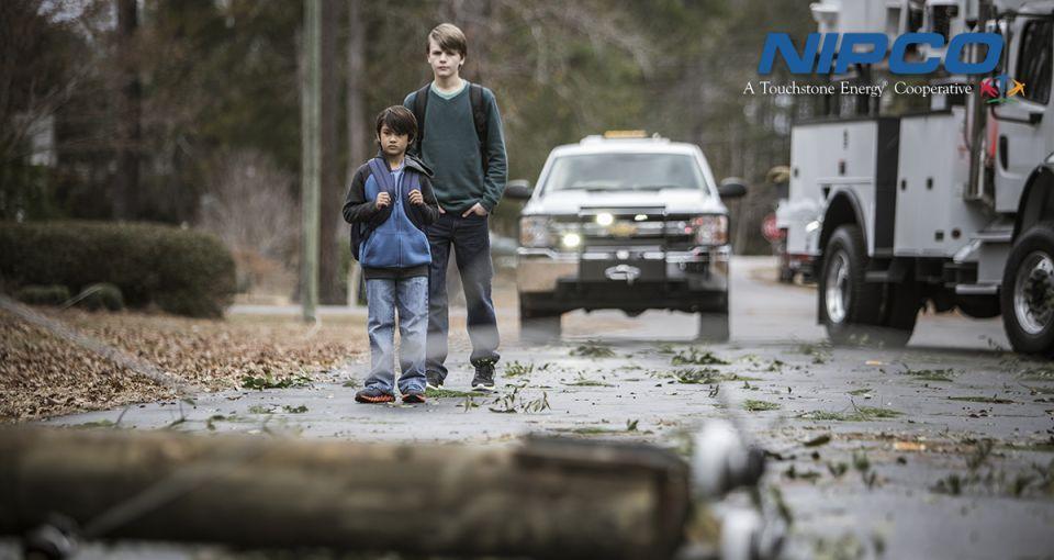 Two kids walking near downed power lines and stop for safety.