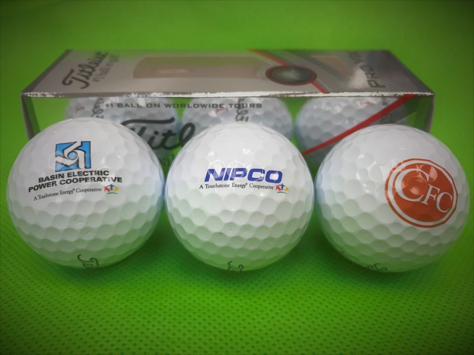 close-up photo of three golf balls and the box they come in