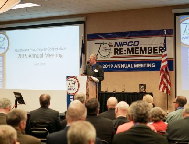 Board President Louis Reed stands at a podium and delivers a speech on a stage with an audience