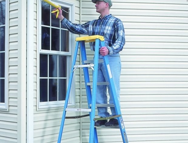 man on ladder caulking