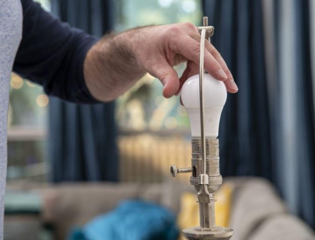 Photo image of a man changing out an LED bulb in a light fixture.