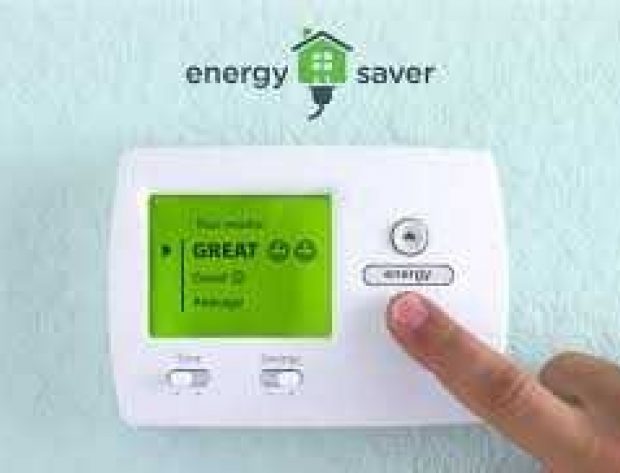 Image from the Department of Energy features a close-up photo of a person's hand, adjusting a wall thermostat