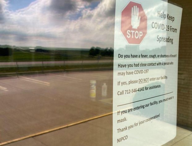 Photo close-up of the warning sign posted on NIPCO's front door about safety protocols before entering the building.