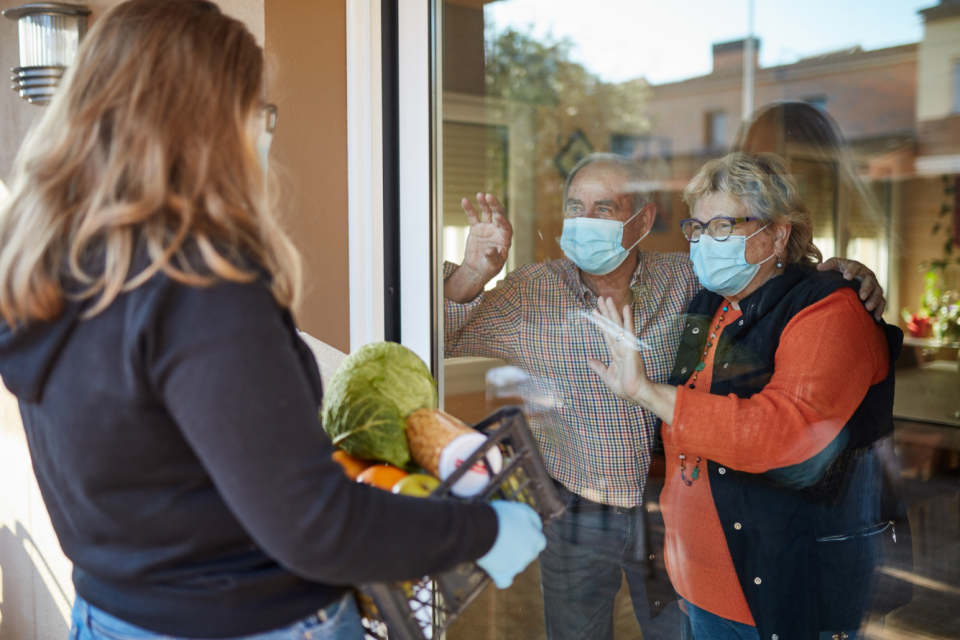 Woman delivering groceries to homebound people with masks on