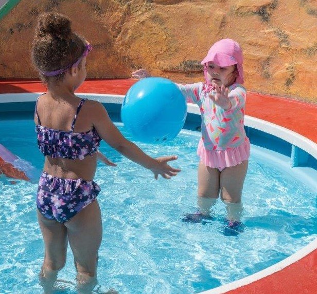 two girls in a small pool with a ball