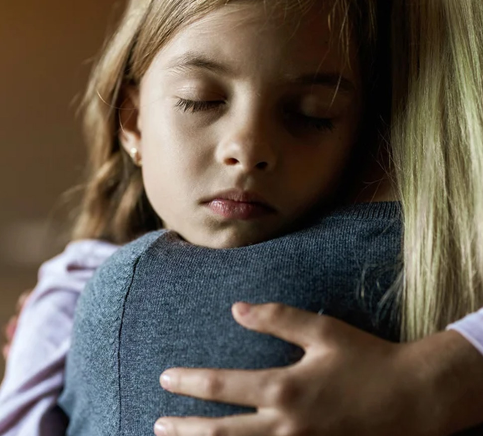 Young girl embraces mother for comfort