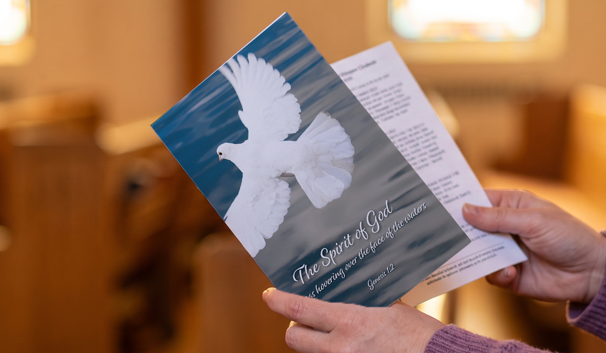 person holding a copy of a Sunday bulletin