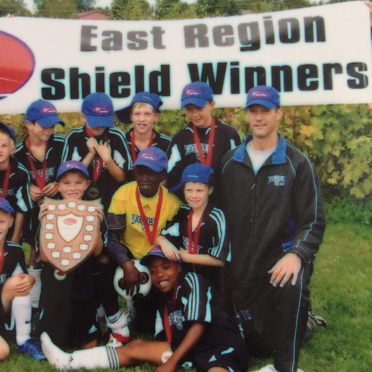 Zoom and Elliot are both in this picture can you spot them? Zoom is sitting on the grass where Elliot is holding the shield playing for their youth club, Ottawa South United.