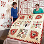 women hold up quilt