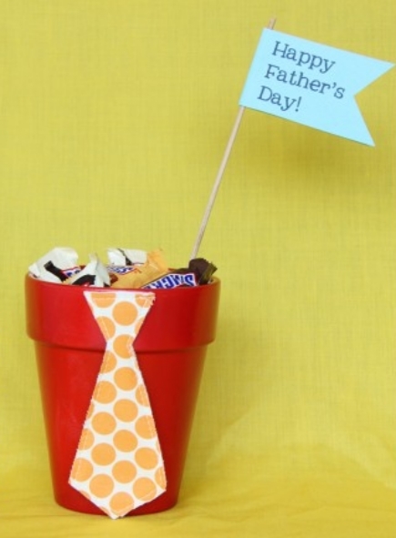 A small, painted flower pot filled with candy and a "Happy Father's Day" flag