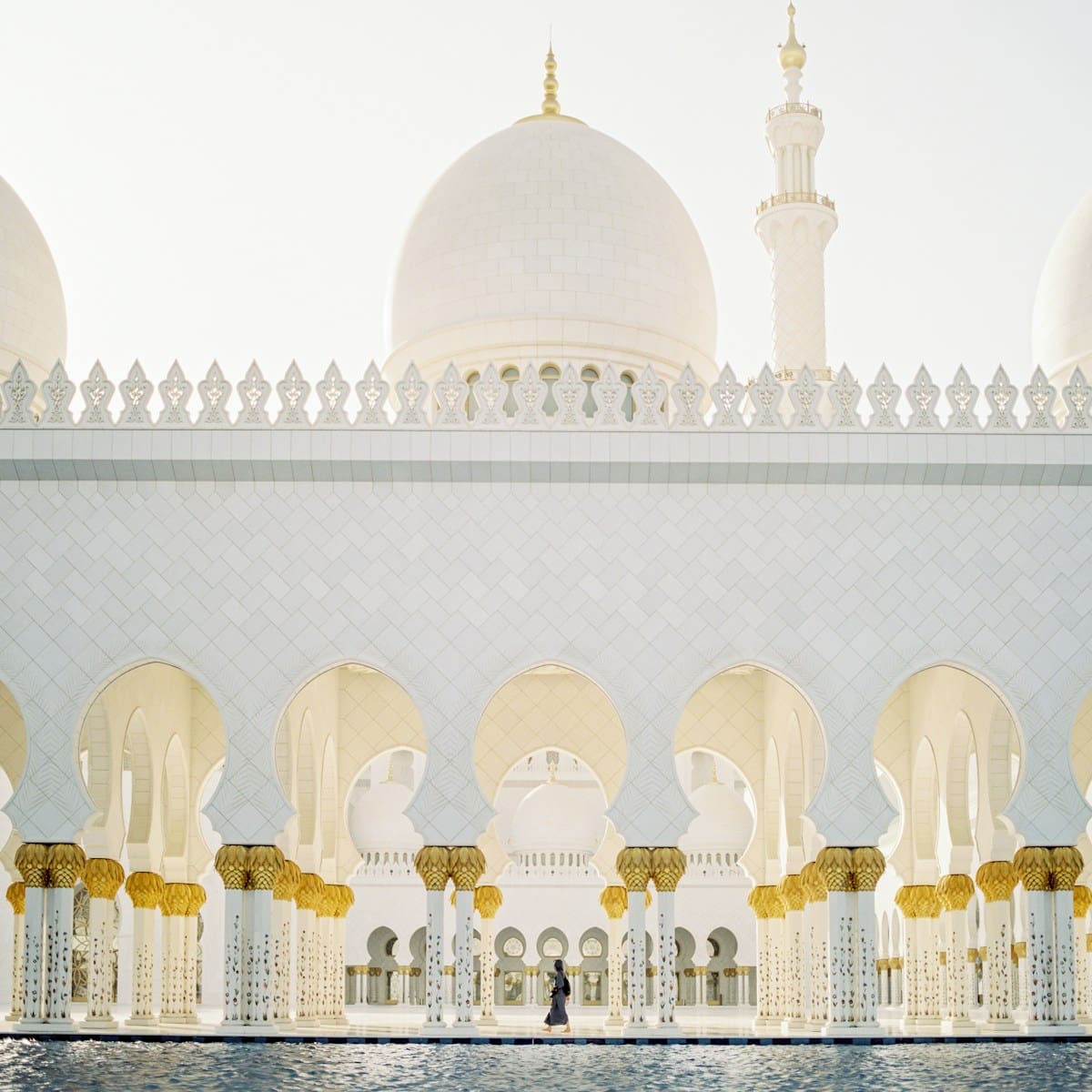 Photo by Dan Freeman person walking inside white concrete mosque during daytime