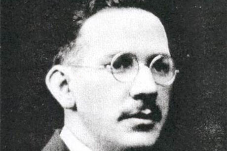Black and white portrait of a man with glasses, a mustache, and wearing a suit and tie.
