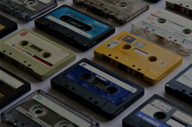 Several vintage audio cassette tapes are arranged in rows on a flat surface.