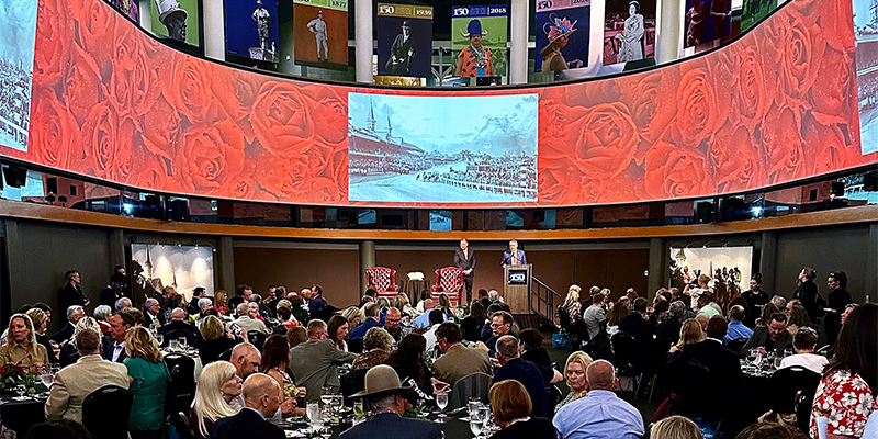 the great hall filled with guests and a red roses screen
