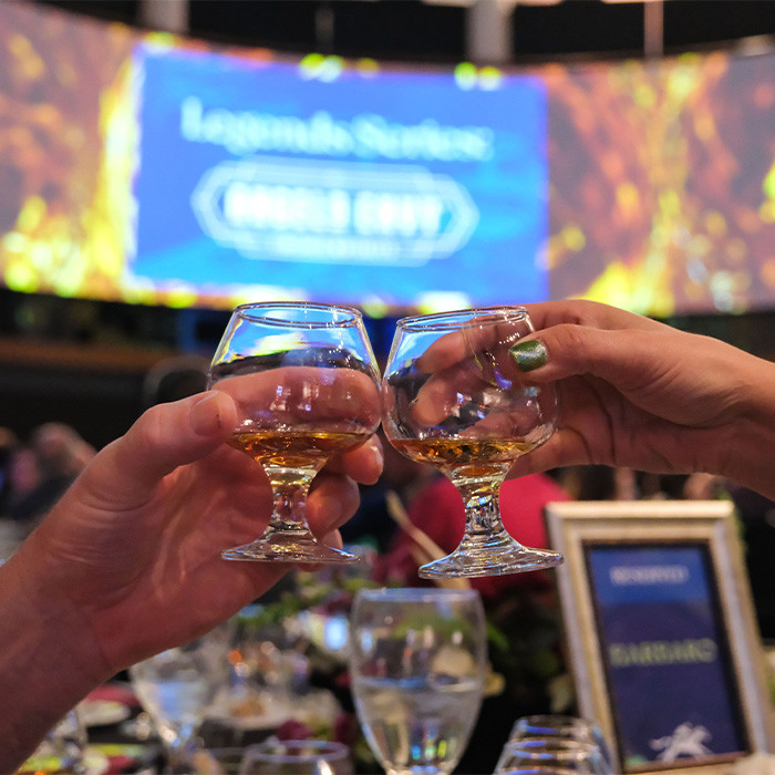 Hands clinking bourbon glasses