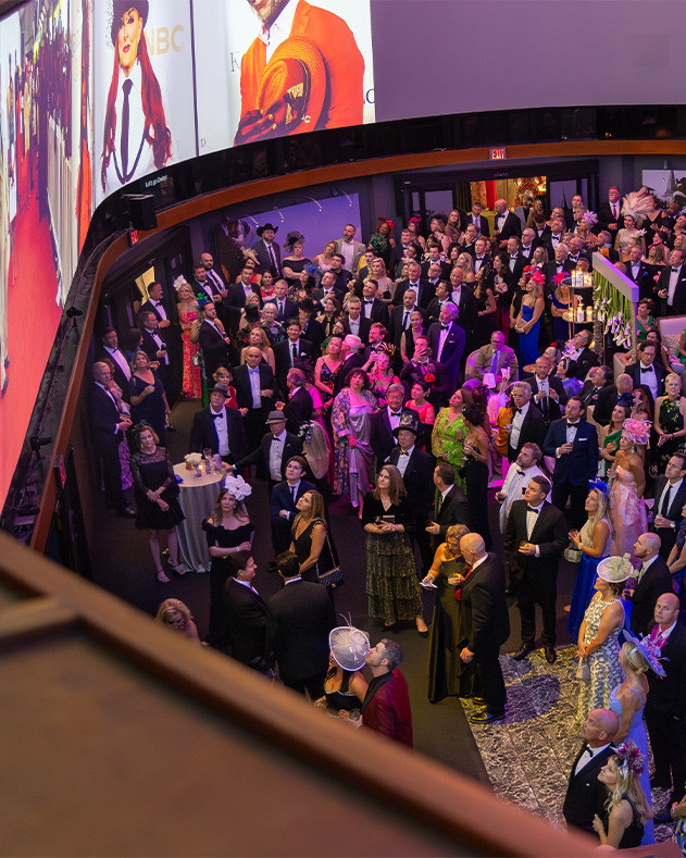 Large group in black tie attire watches The Greatest Race movie