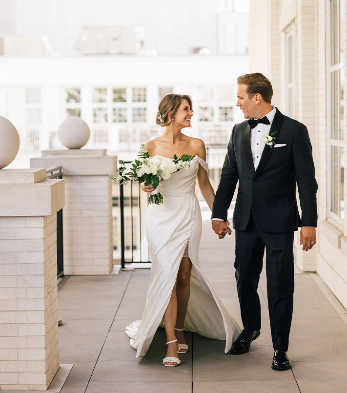 Bride and Groom on balcony of white brick and stone