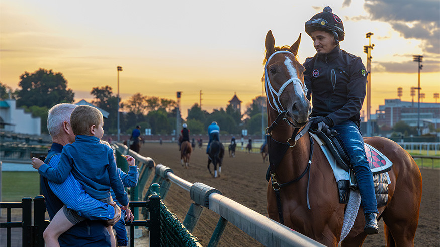 Family standing next to horse and riders on Churchill Downs Racetrack