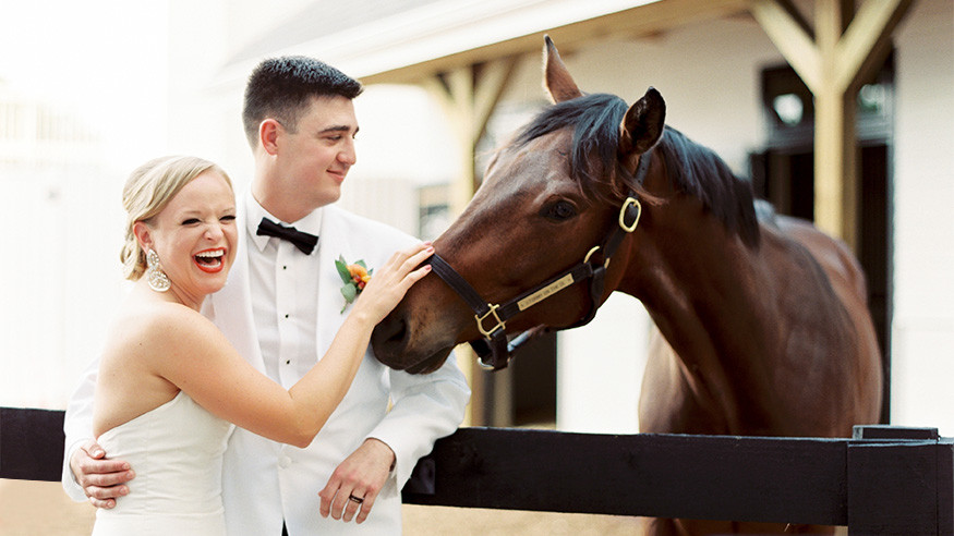 Bride and Groom with Thoroughbred horse in stable