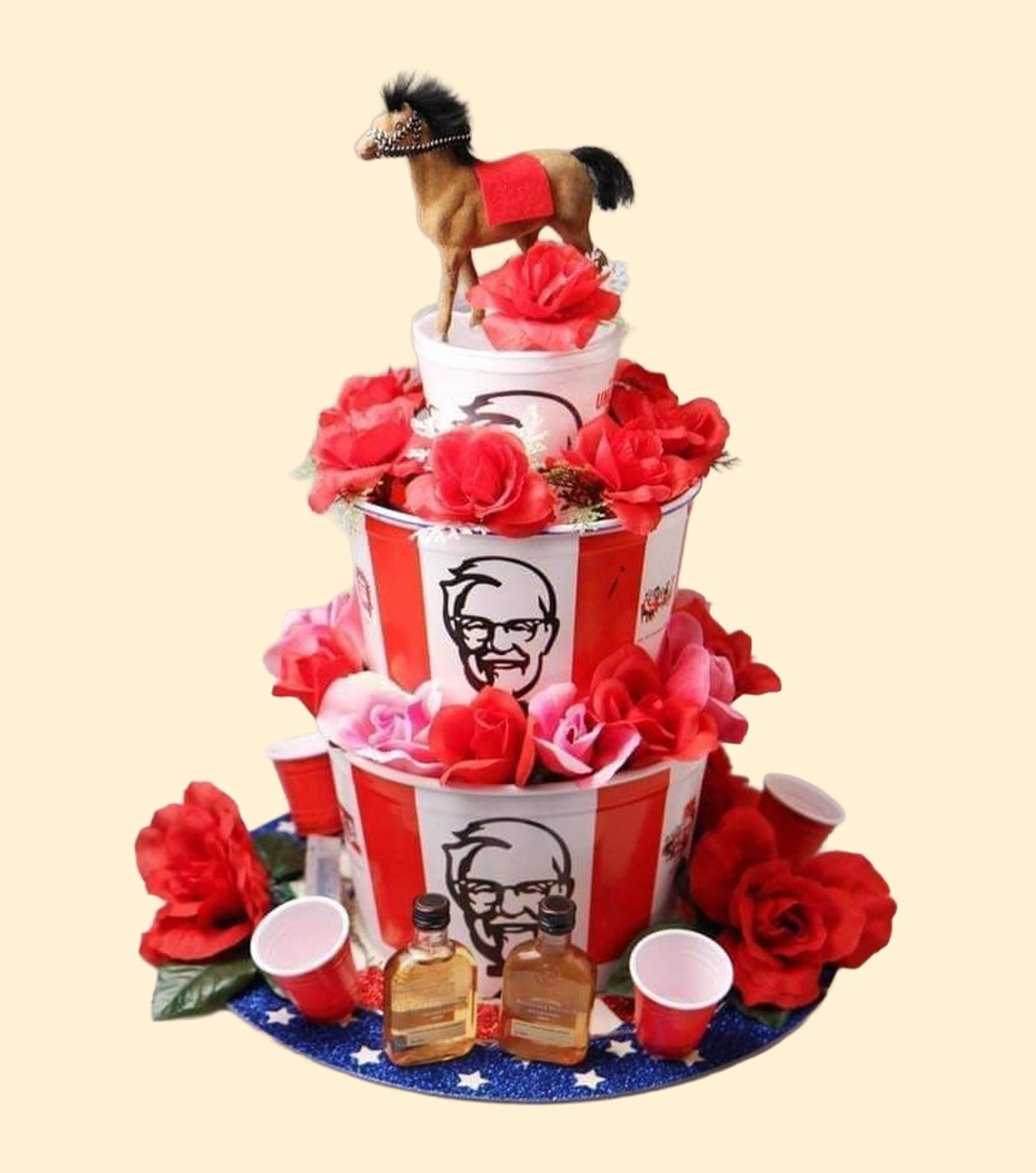 KFC buckets tiered with roses and bourbon around them and a horse sitting on top
