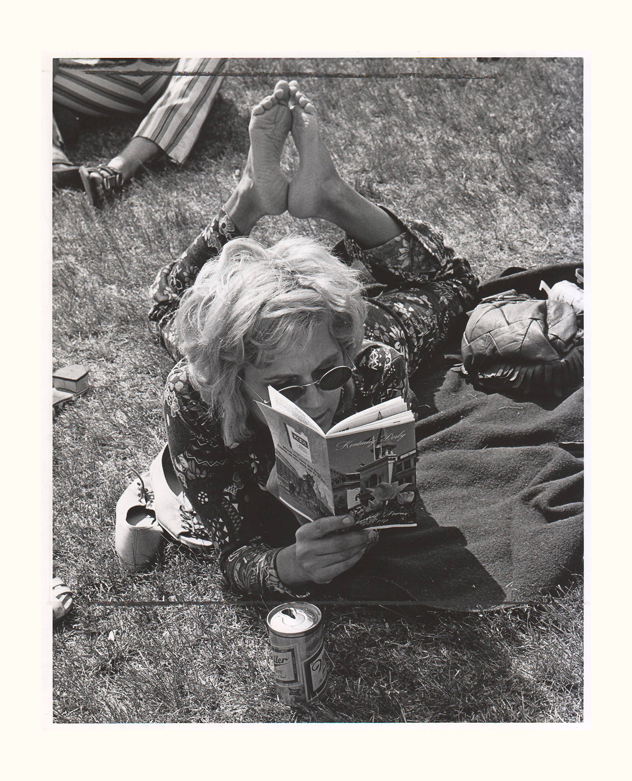 woman reading a book on the grass at the 1971 kentucky derby