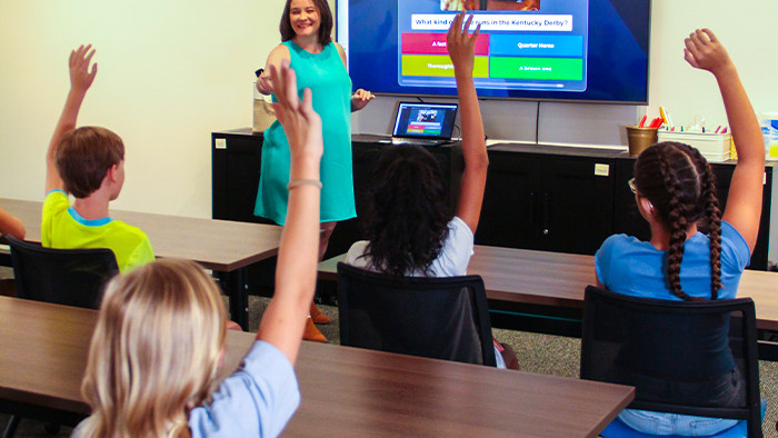 teacher leading virtual field trip programming as students raise their hands