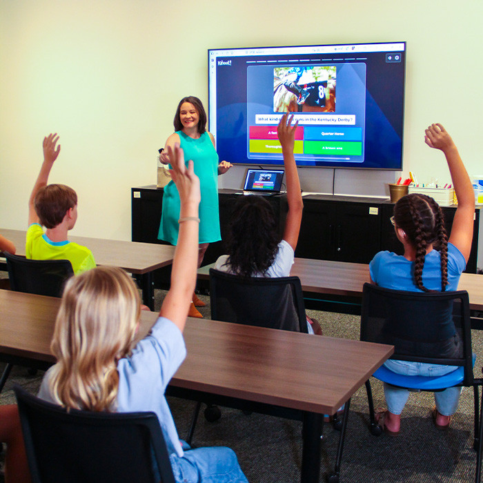 teacher leading virtual field trip programming as students raise their hands