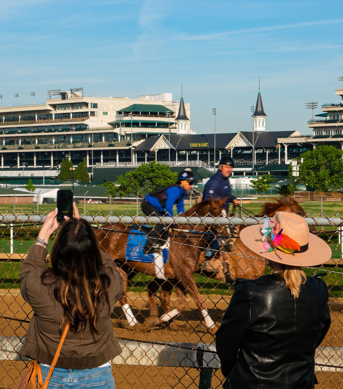 two women taking pictures of a horse on the backstretch