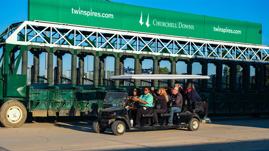Guests riding golf cart in front of official track starting gate