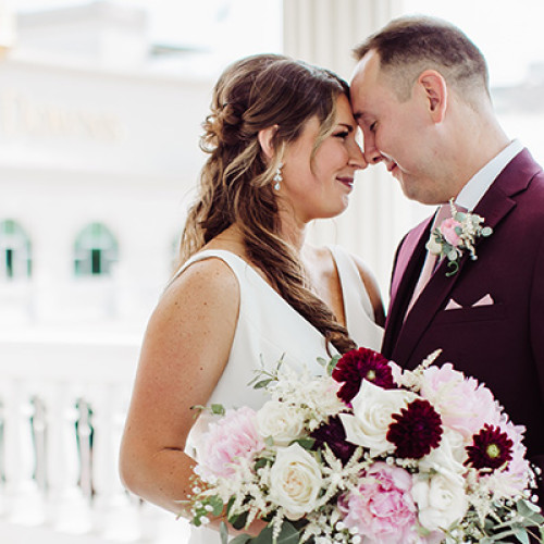couple holding a bouquet of flowers together on the 2nd floor gallery balcony