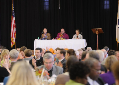 Bishop, flanked by chancellor and secretary of the diocese, chairs convention from the parish hall stage