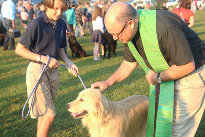 ESK Sixth Grader Barrett Parker (left) holds onto his dog while The Rev. John Tirro (right), of Tyson House, Episcopal-Lutheran Campus Ministry at UT Knoxville, performs a blessing at ESK’s annual Blessing of the Animals event. 