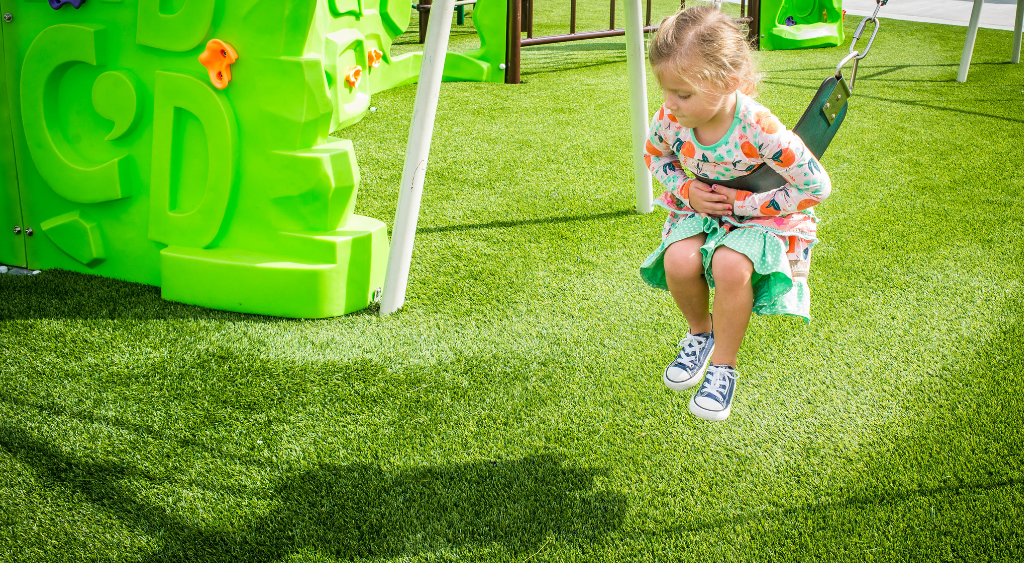 child on swing artificial turf playground jacksonville