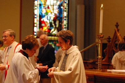 The presiding bishop serves a choir member during communion