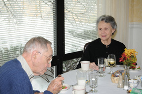 Mr. and Mrs. Marshall Hardy pictured at a table in the Episcopal Church Home's dining room, seated in front of a window with a view of the snow just behind them