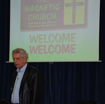 Andrew Weeks lectures with a Power Point visual behind him that welcomes his audience to the Magnetic Church conference
