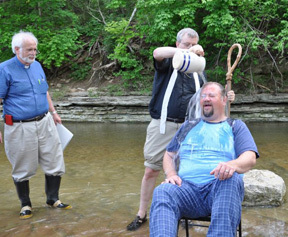 Bishop Ted Gulick pours the creek water of baptism over Mike Yade as Ascension rector Karl Lusk watches