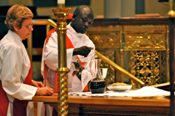 Deacon Daniel Kuol fills the chalice with wine as Deacon Rose Bogal-Allbritten assists