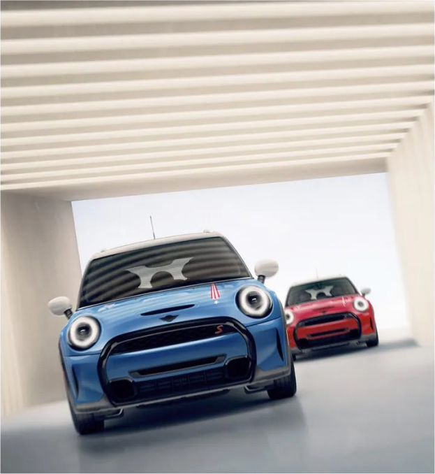 Front views of two MINI 20 Years Edition vehicles, one in Island Blue and one in Chili Red, underneath a square beige entranceway with stripes overhead and a clear sky in the background.