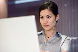 Woman with Headphones Working at Computer