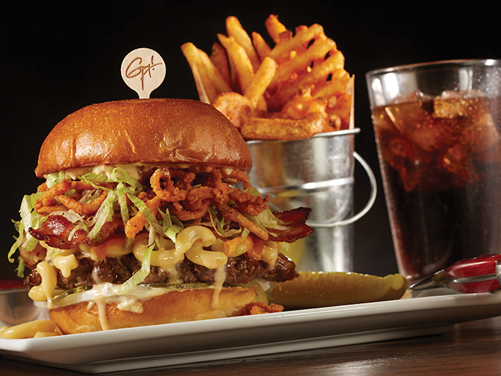 The Bacon Mac N Cheese burger platter with a pickle, bucket of fries and soft drink
