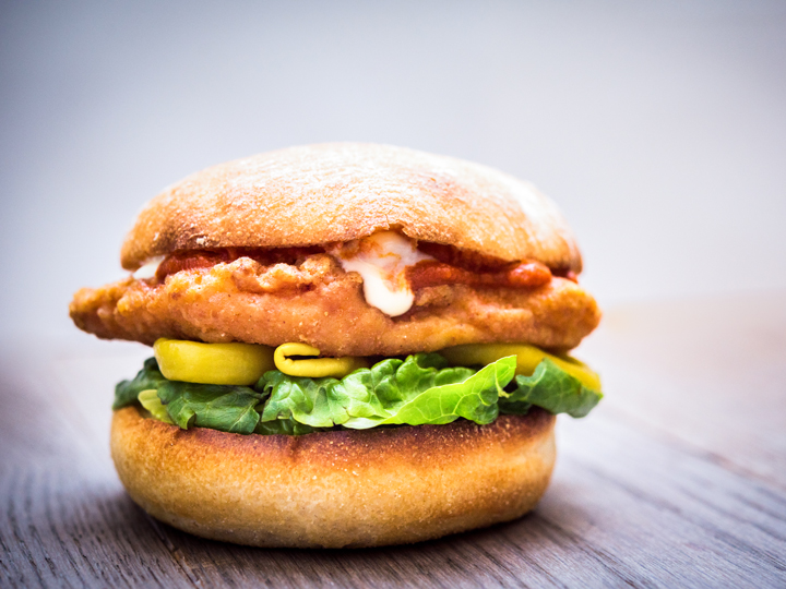 A sandwich with a fried chicken patty, jalapenos, lettuce and other ingredients