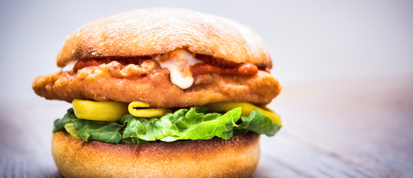 A sandwich with a fried chicken patty, jalapenos, lettuce and other ingredients